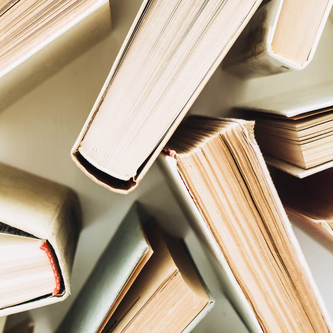 A stack of open books photographed from above, with the pages visible and warm lighting.