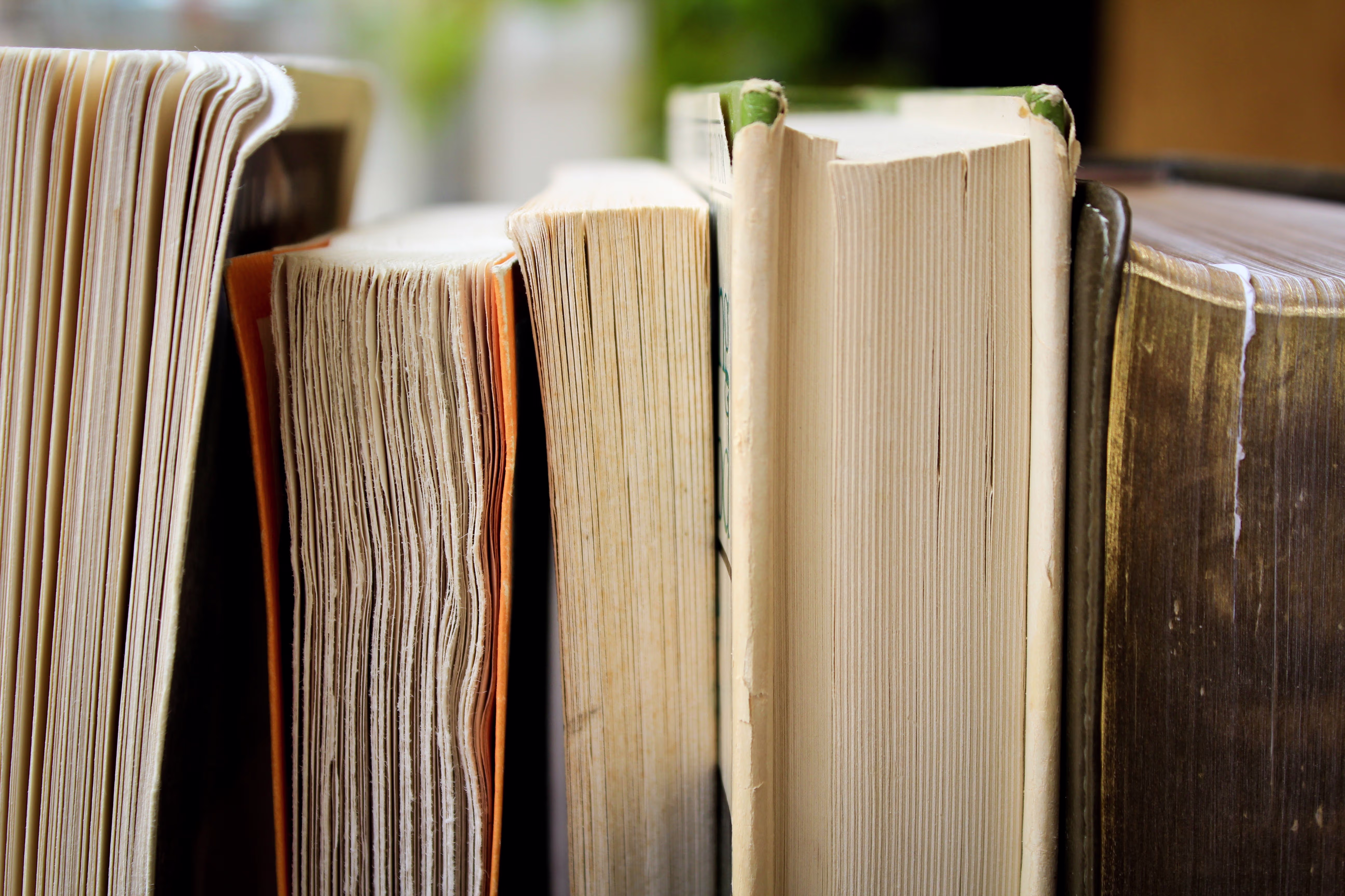 Een rij oude, versleten boeken staat naast elkaar, waarbij de pagina's en ruggen duidelijk zichtbaar zijn.