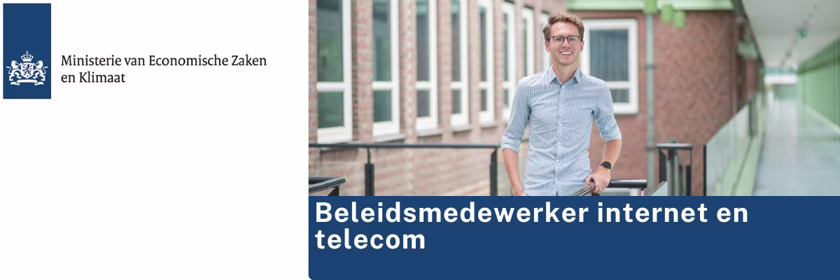 Een man in blauw overhemd staat buiten bij een bakstenen gebouw, met tekst 