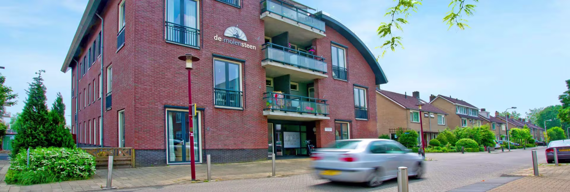 Exterieur van appartementencomplex De Molensteen, een rood bakstenen gebouw met balkons in een woonwijk.