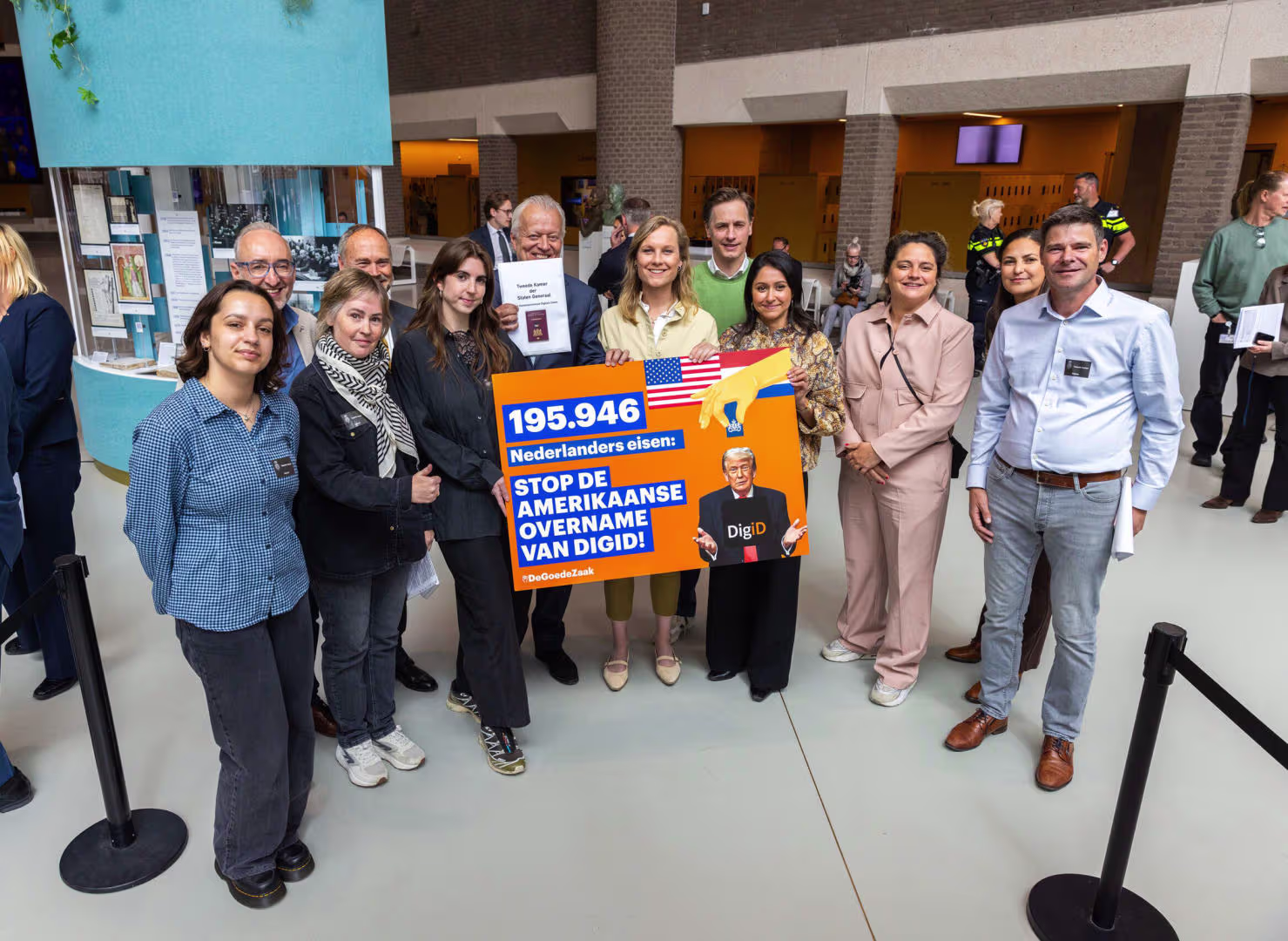 A group of people poses in a building with an orange sign: 