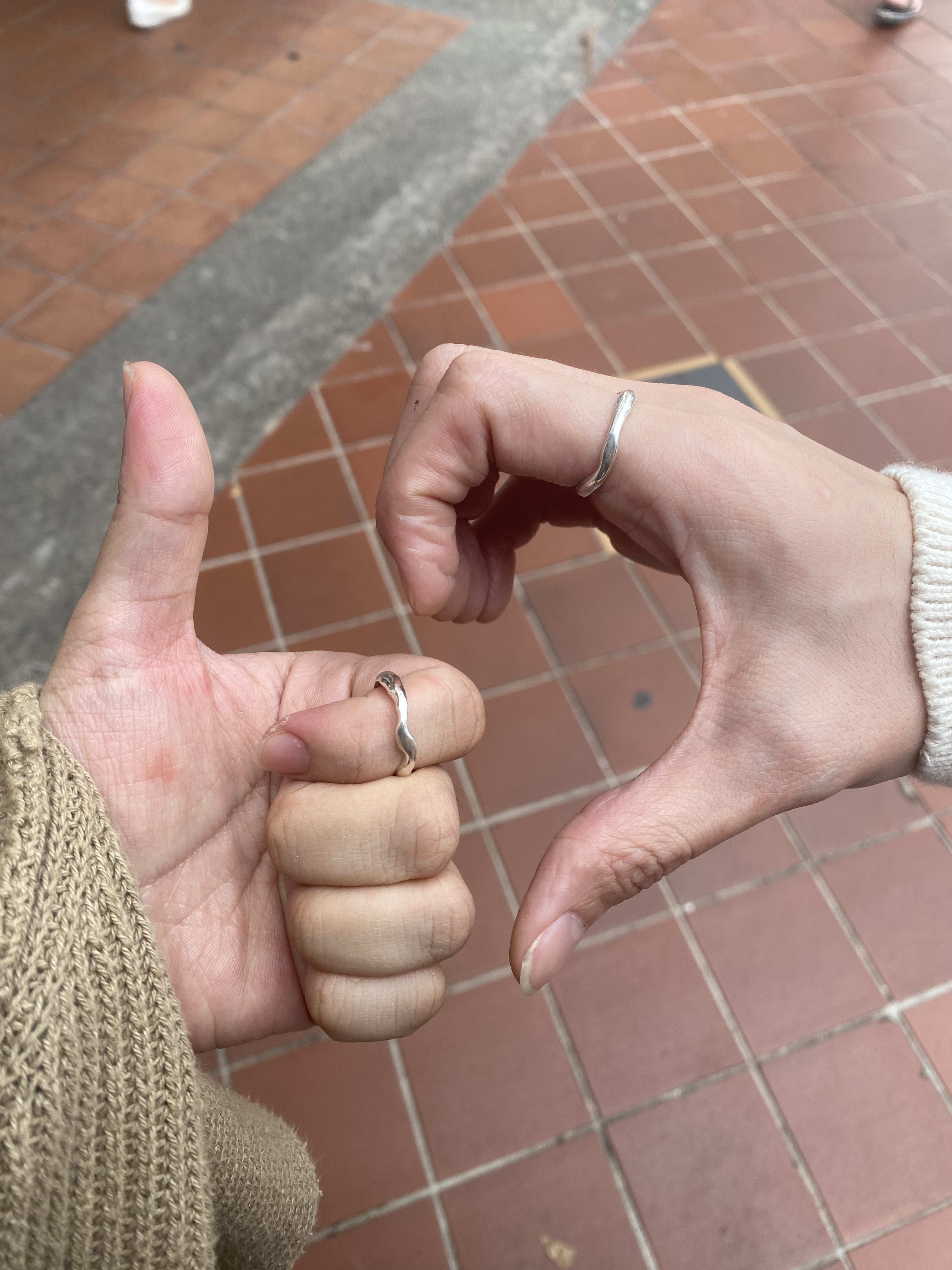 Two hands posing with rings on the index finger