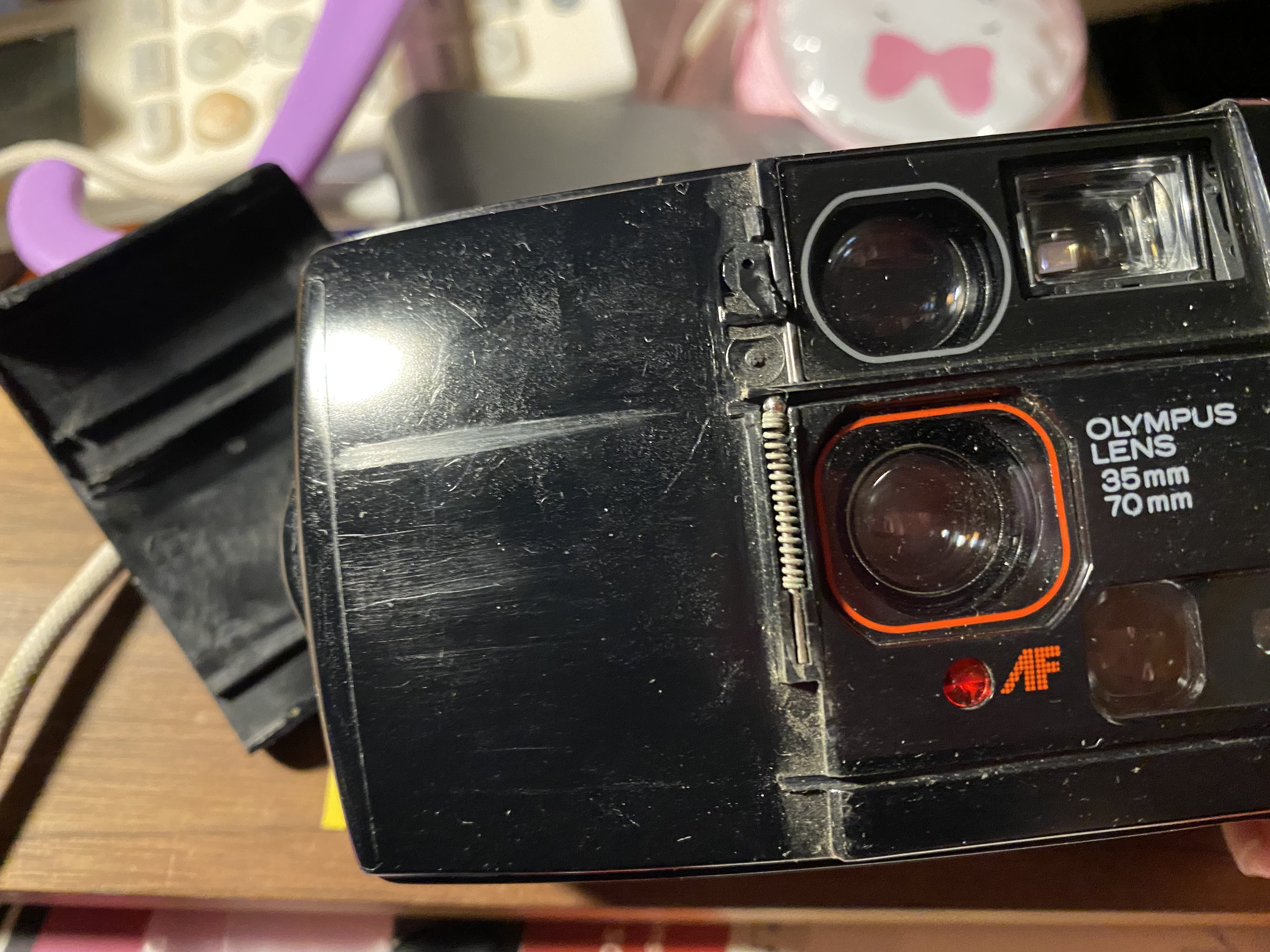 Close-up of a Olympus AF-1 Twin camera. The lens cover has been removed to expose the front of the camera.