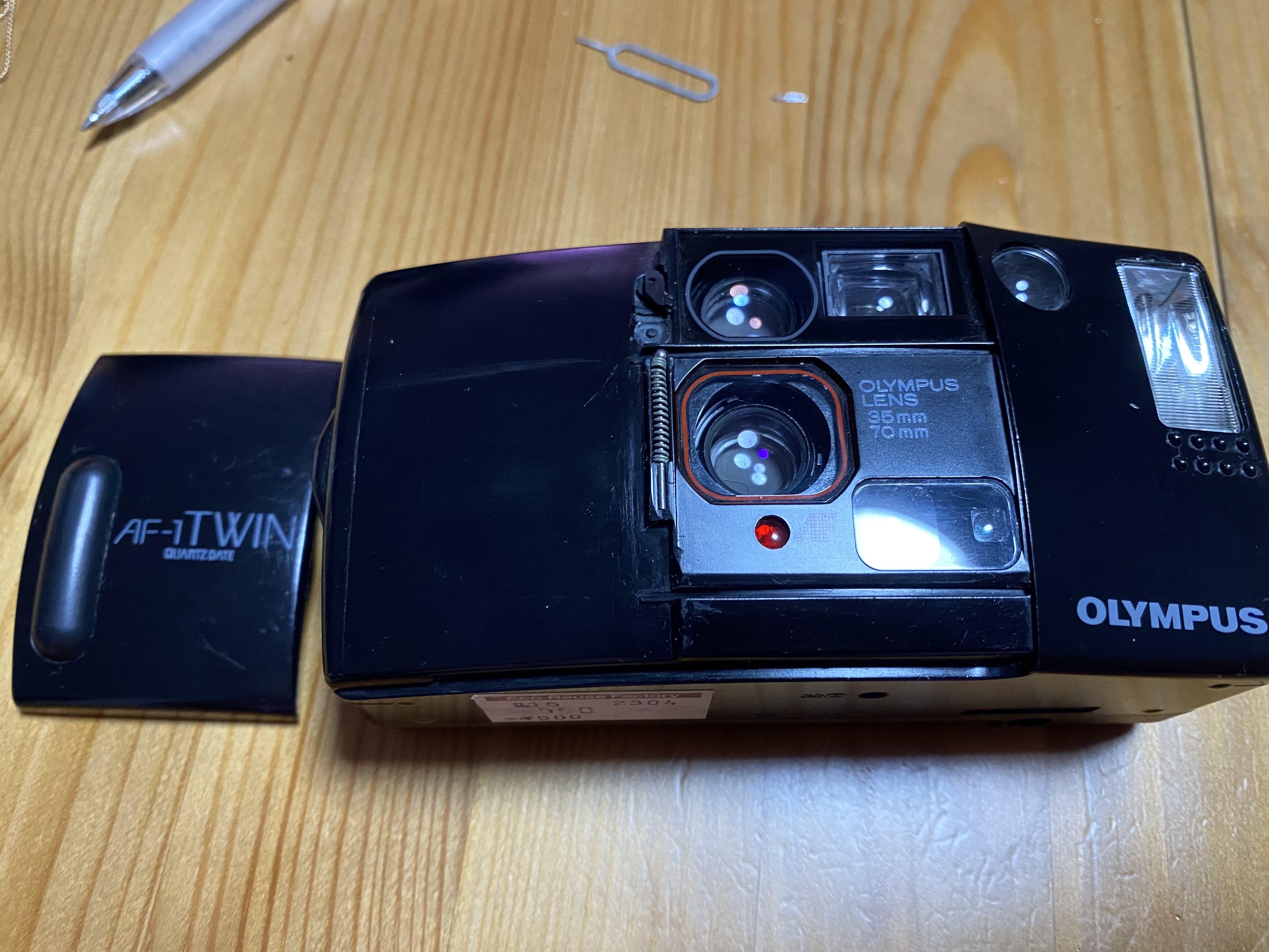 Olympus AF-1 twin shown with the camera body and lens cover side by side.