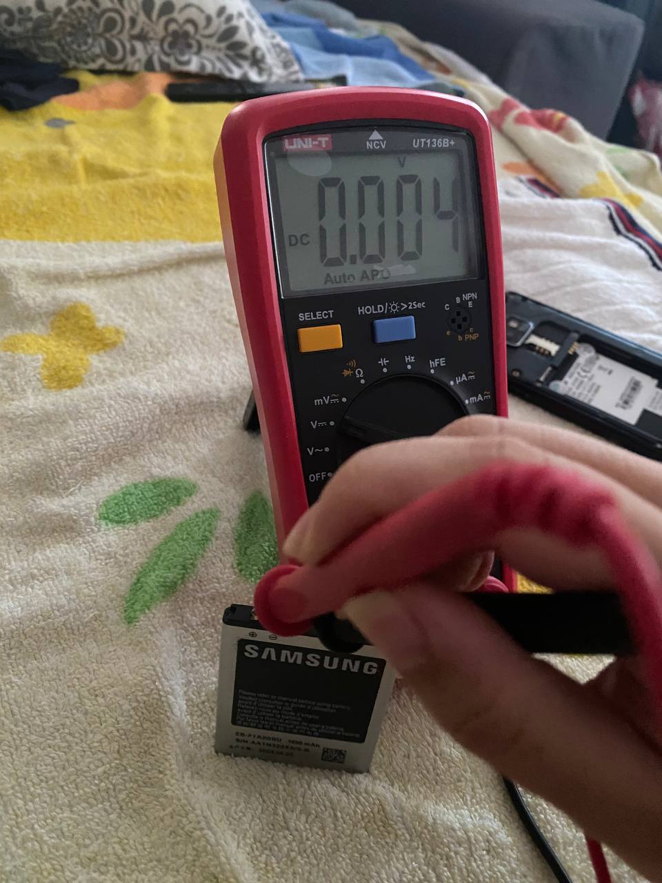 Multimeter reading showing a samsung galaxy s2 battery measuring 0.004v