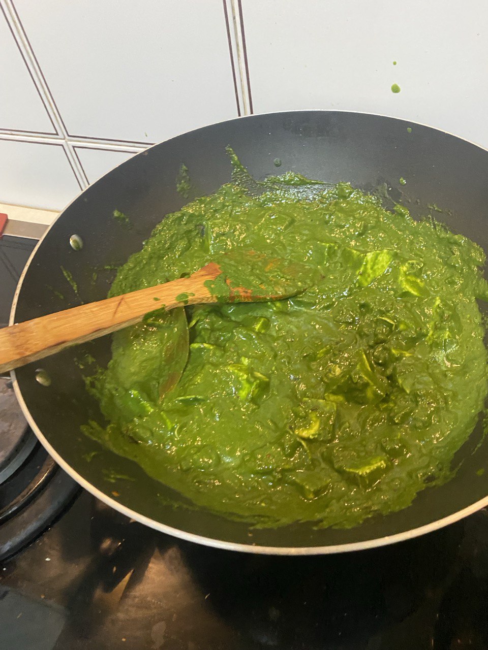 Palak paneer simmering on the stove in a wok