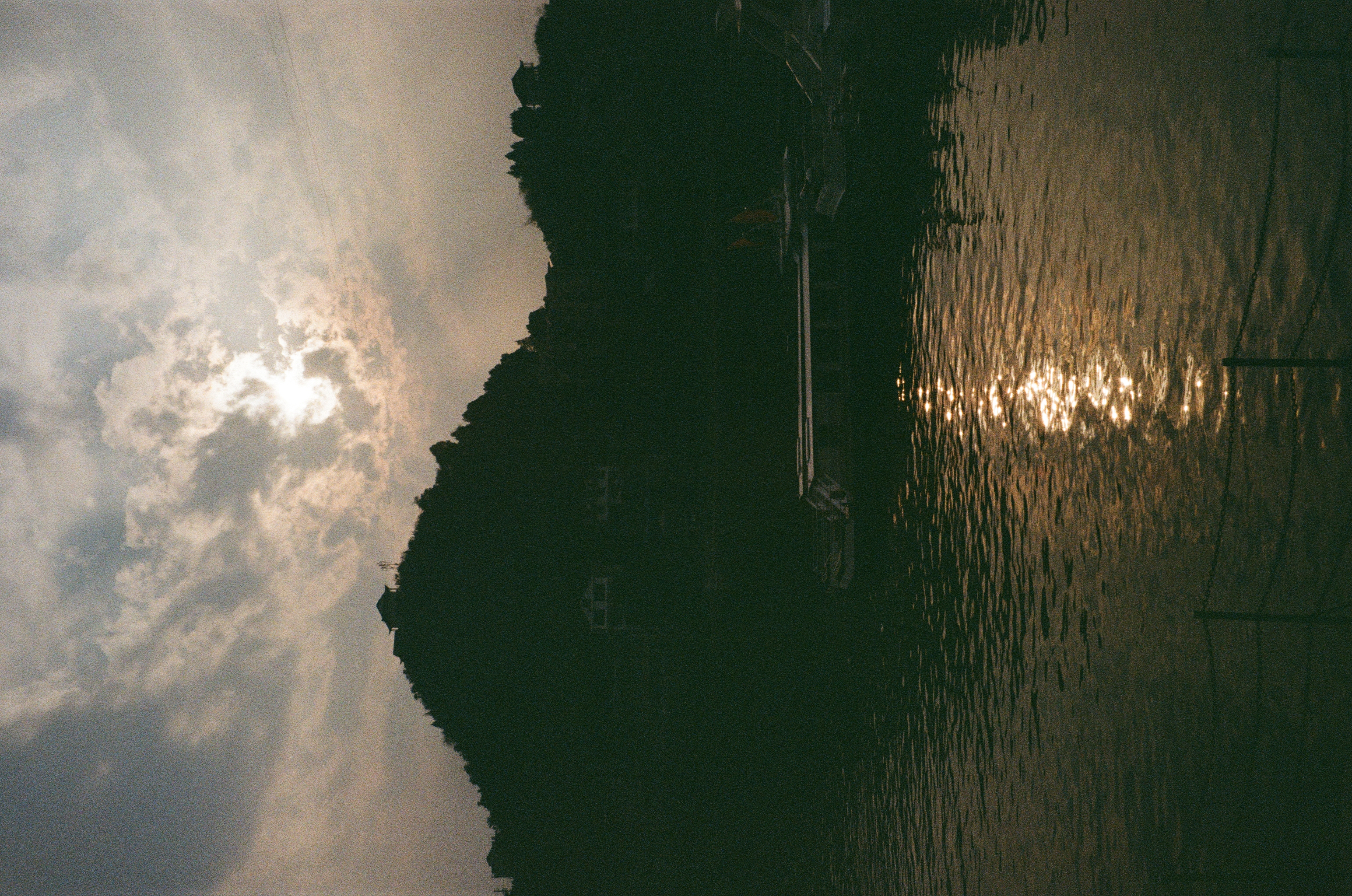 A cloudy day in Hunan. A backlit hill appears in the background, while the water in in the foreground is dappled with sunlight.