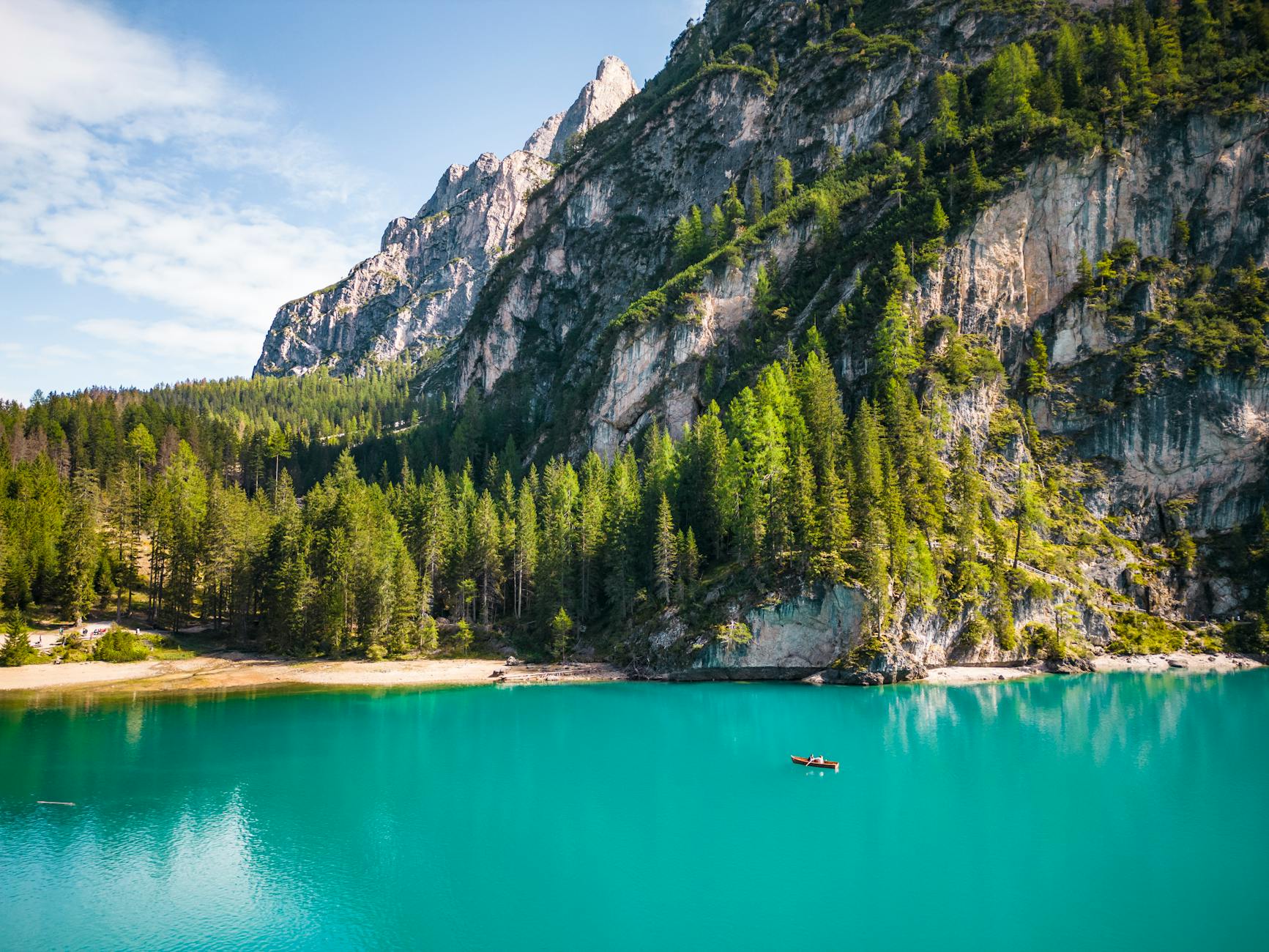 Explore the stunning turquoise waters of Braies Lake surrounded by lush forests and majestic mountains in the Alps.