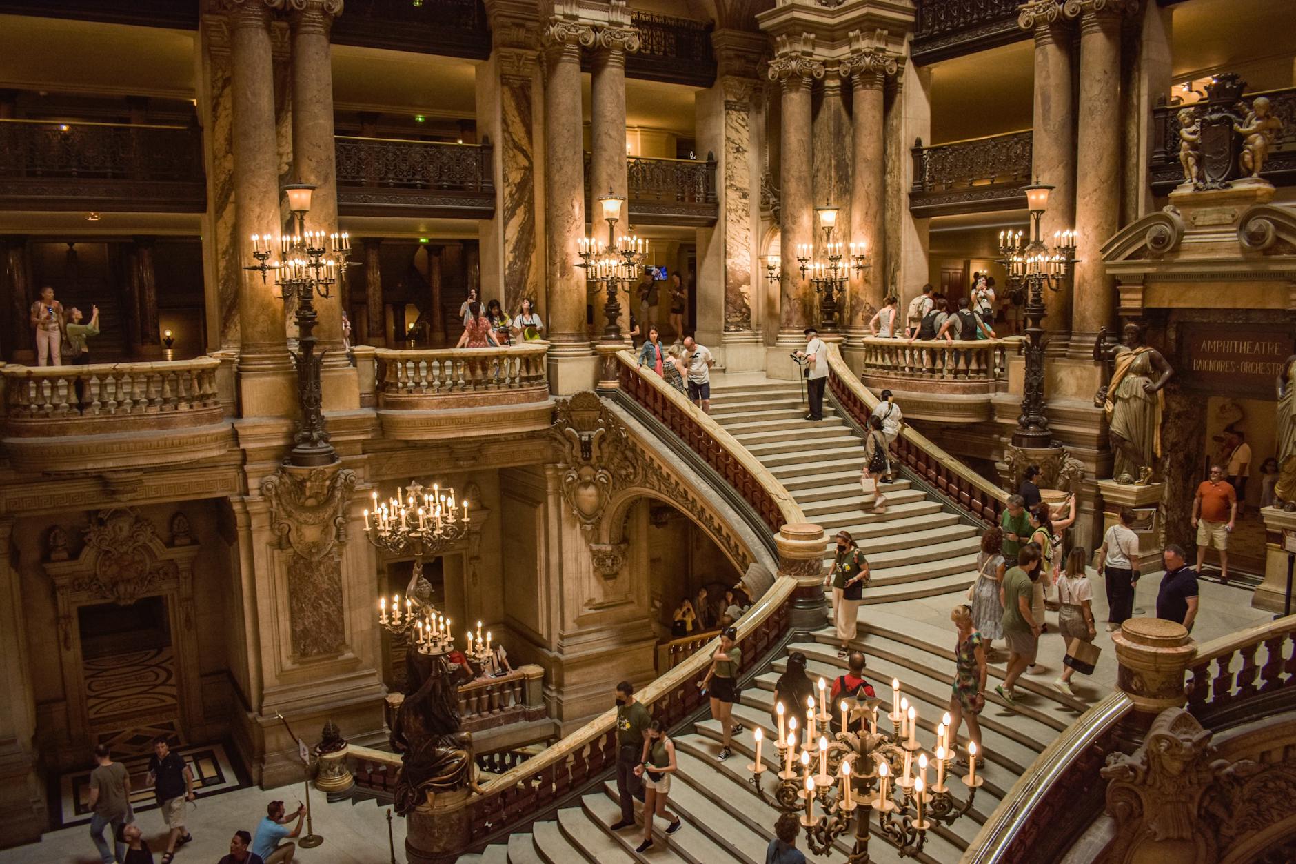 Visitors explore the grand staircase inside the opulent Paris Opera House in France.