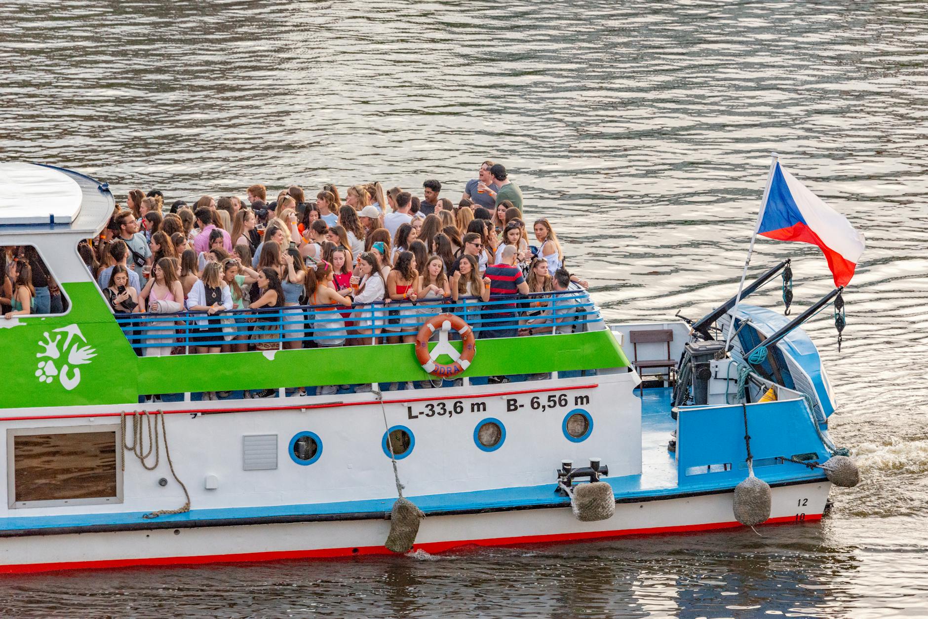 A sightseeing boat filled with tourists on the Vltava River in Prague.