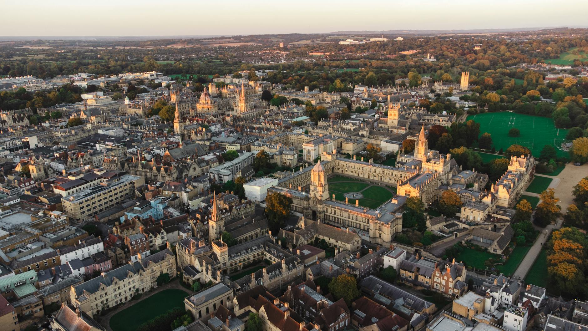 Stunning aerial view of Oxford's historic architecture and green spaces at sunset.
