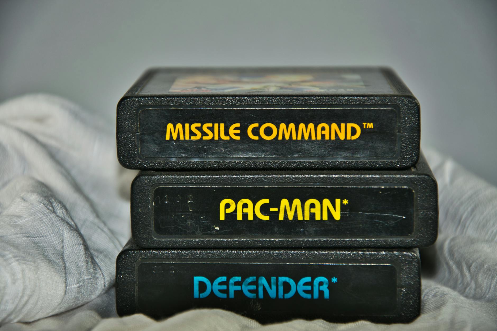 Close-up of vintage Atari game cartridges for Missile Command, Pac-Man, and Defender.