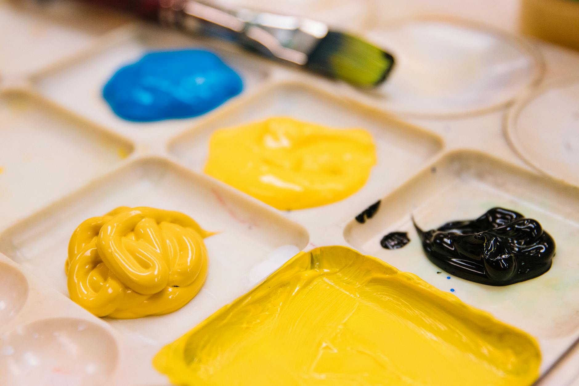 Close-up of colorful acrylic paints on a palette with brush, showcasing artistic creativity.