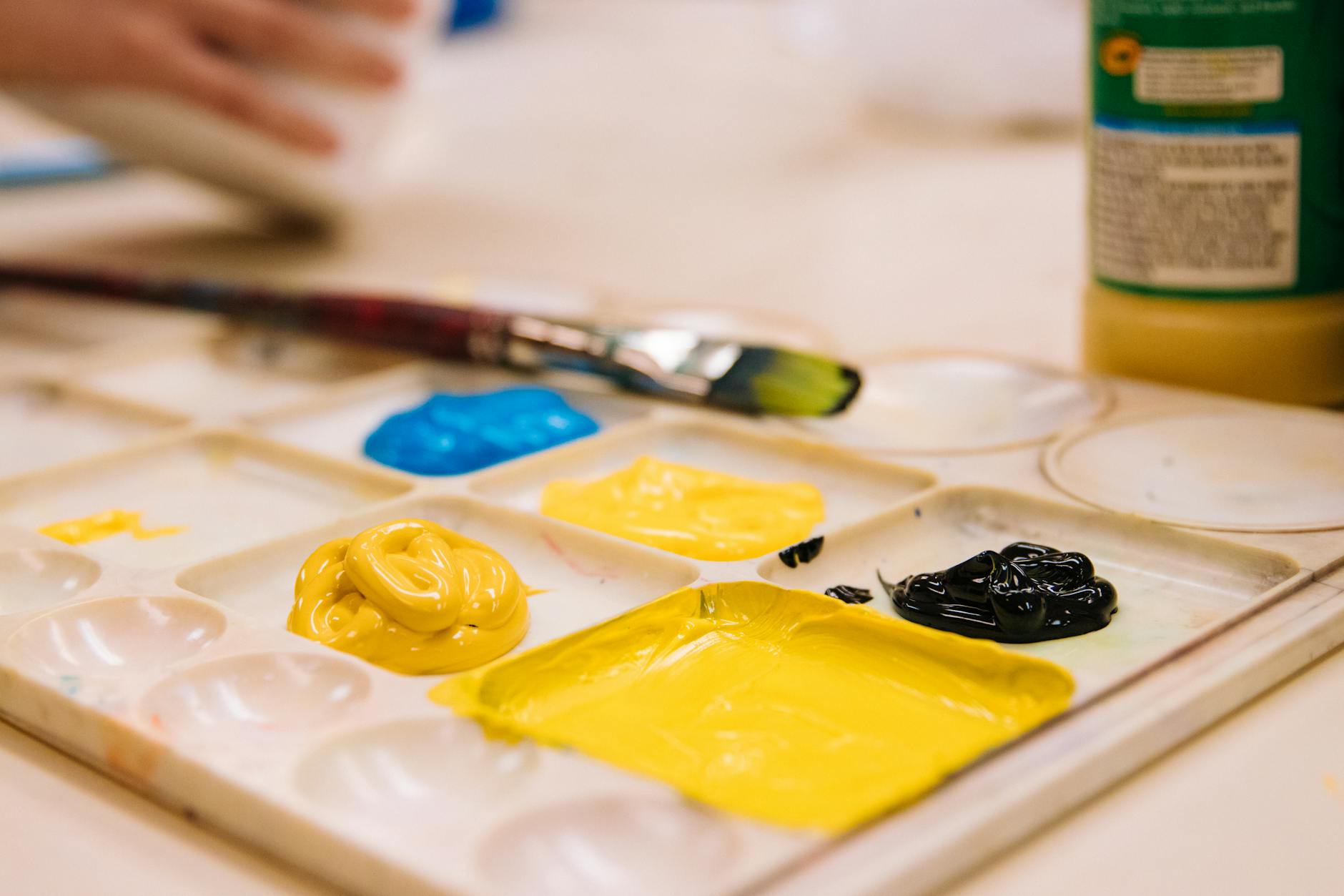 Close-up of a paint palette with vibrant colors and a brush, perfect for art and creativity.