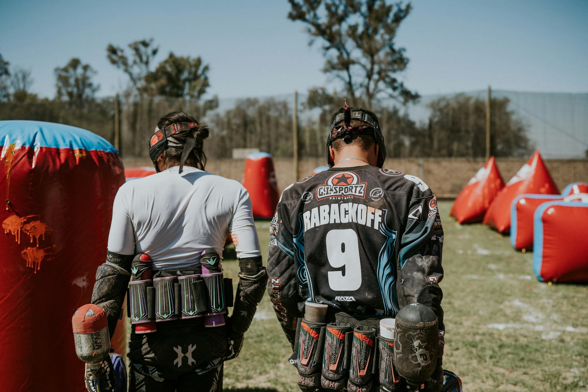 Two players in action on a paintball field, equipped and ready for the game.