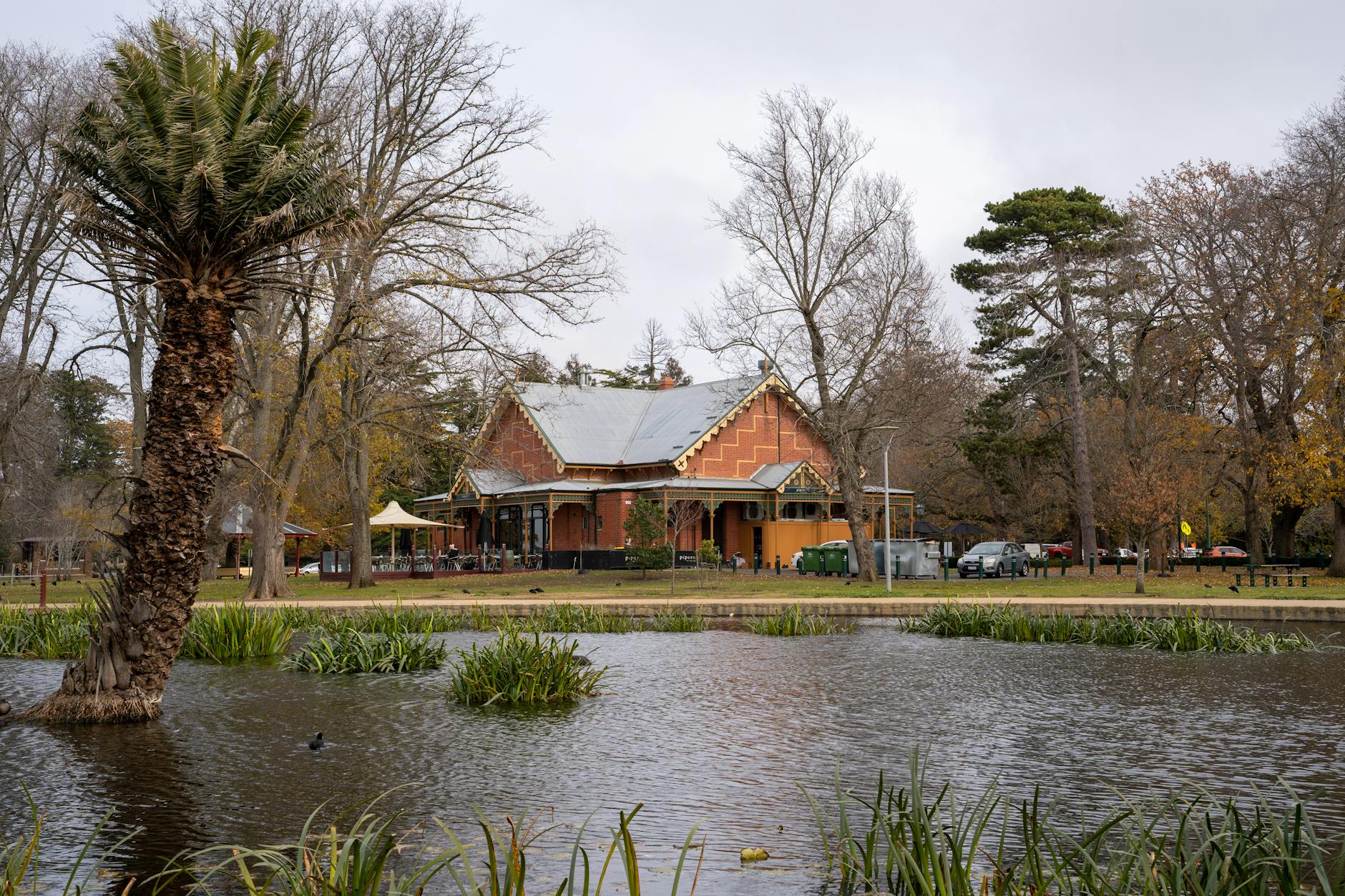 A serene park scene featuring a historic building beside a peaceful pond in Australia, capturing a tranquil moment.