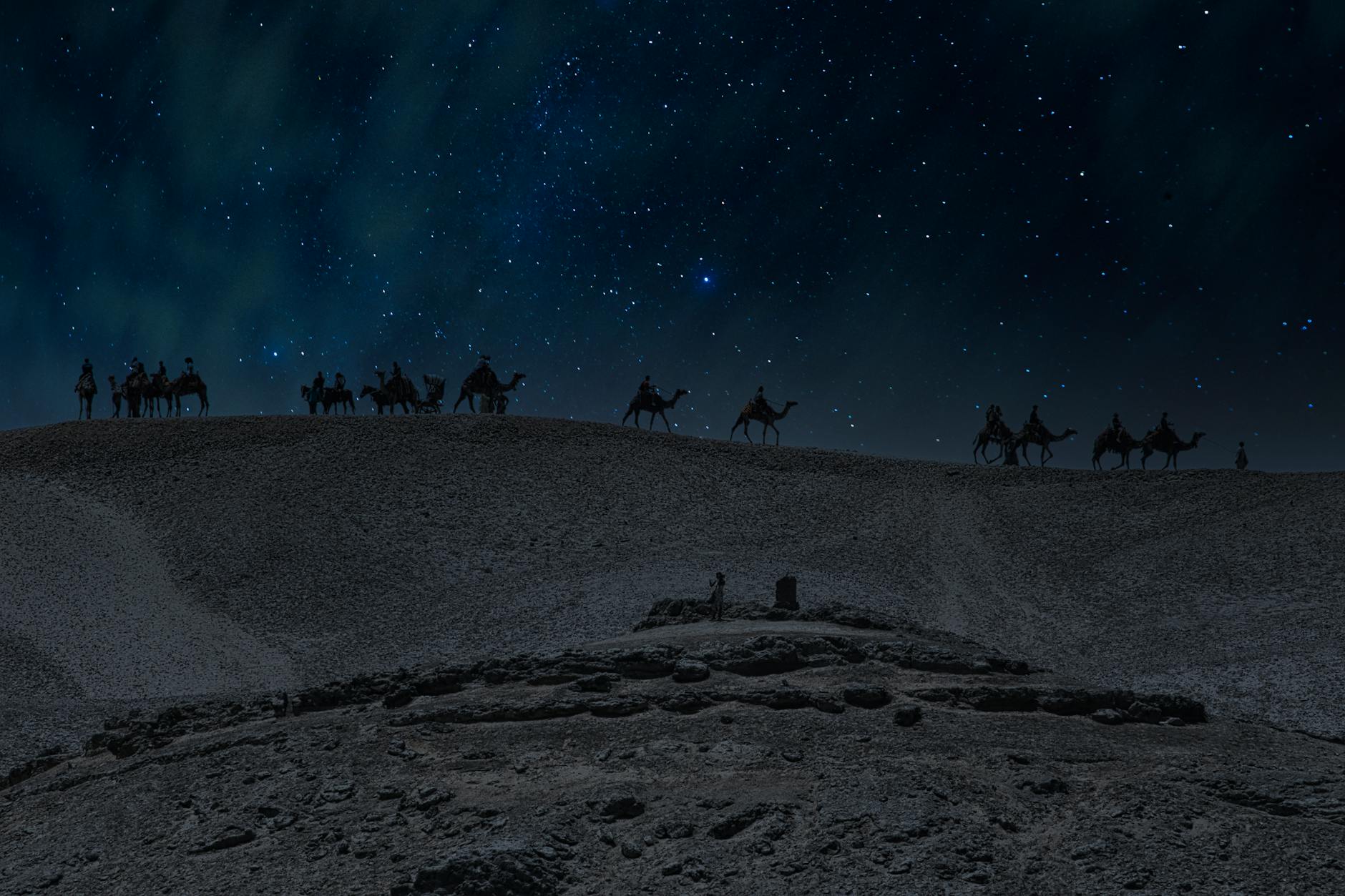 A camel caravan under a starry night sky in Egypt's desert landscape.