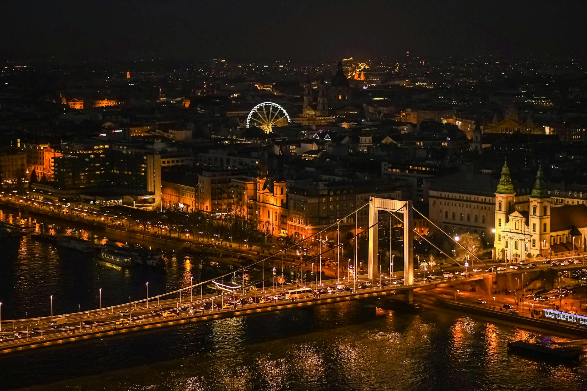 A stunning nighttime aerial view of Budapest featuring the Elizabeth Bridge and Ferris wheel.