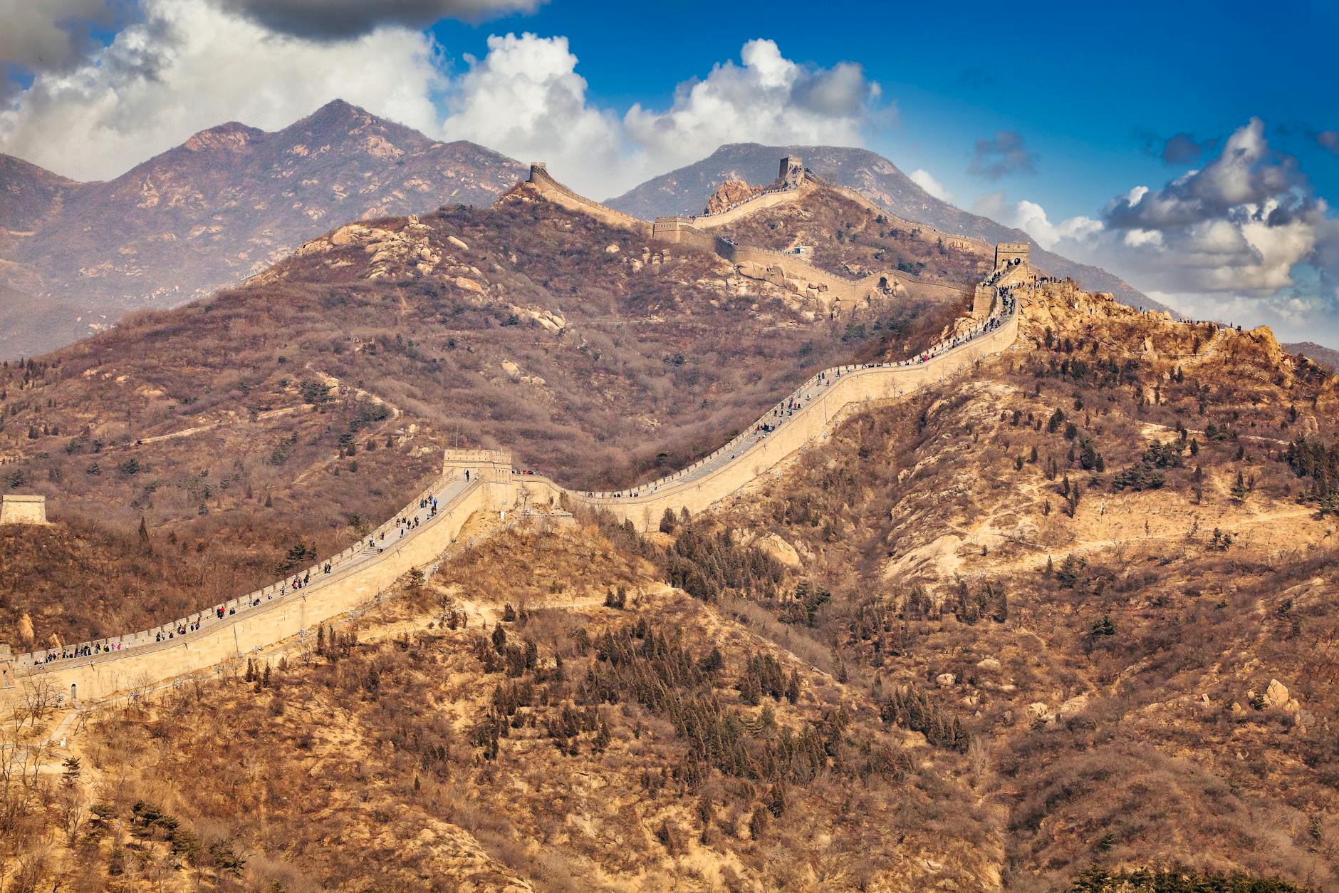 Scenic view of the Great Wall weaving through the mountainous terrain under a blue sky.