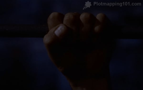 A man running from the police reaches up to the rung on the ladder, his palm and knuckles toward the viewer.