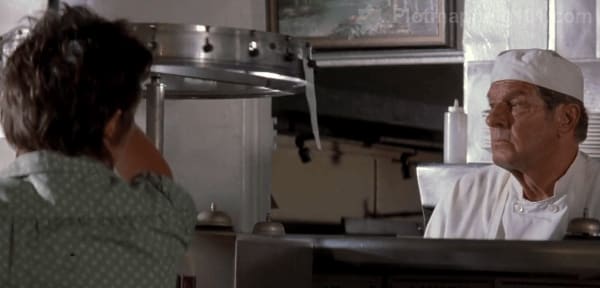 Two men in front of the order wheel at the diner counter.