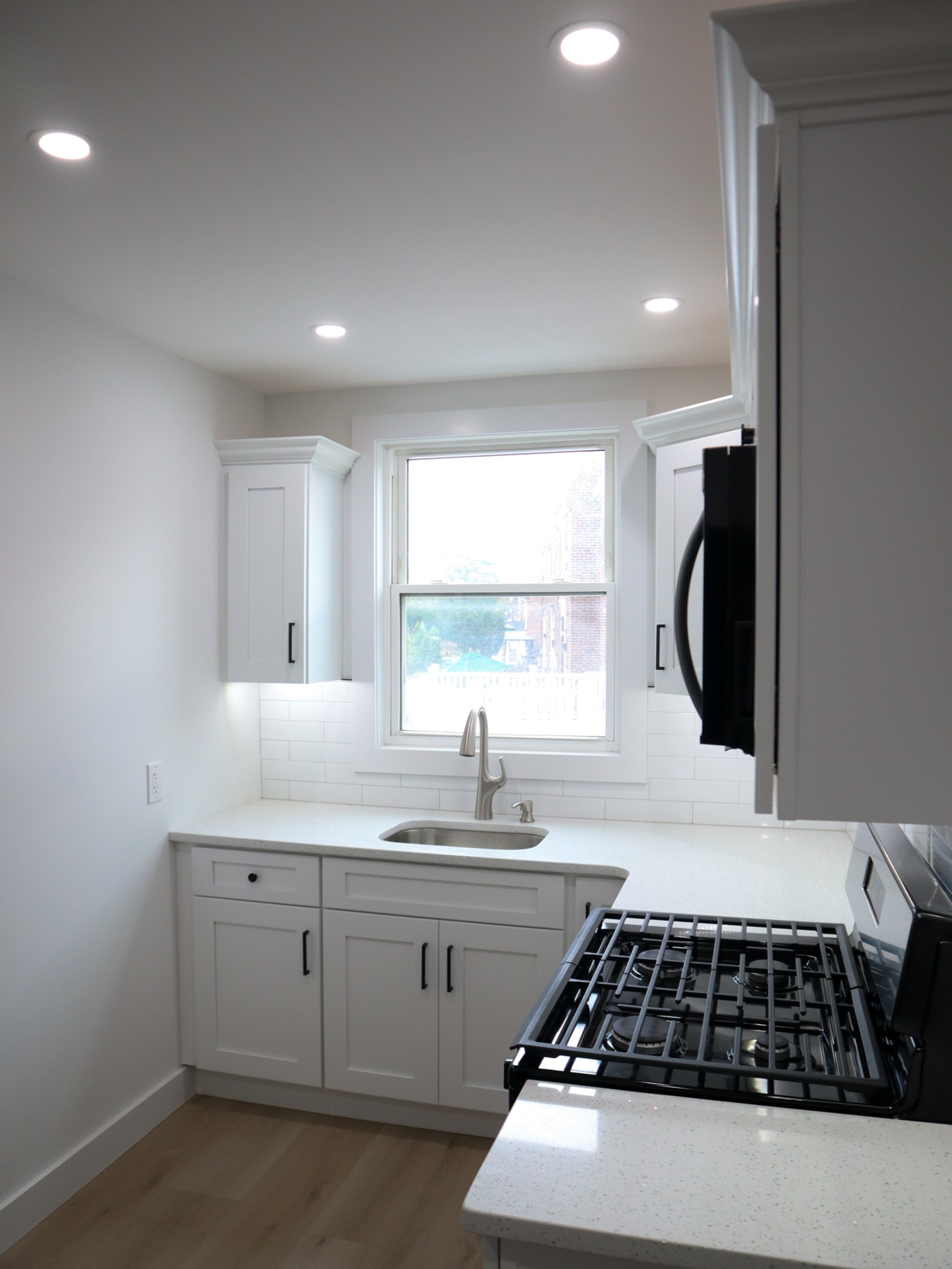 Finished kitchen remodel with white cabinets, subway tile backsplash, and stainless refrigerator
