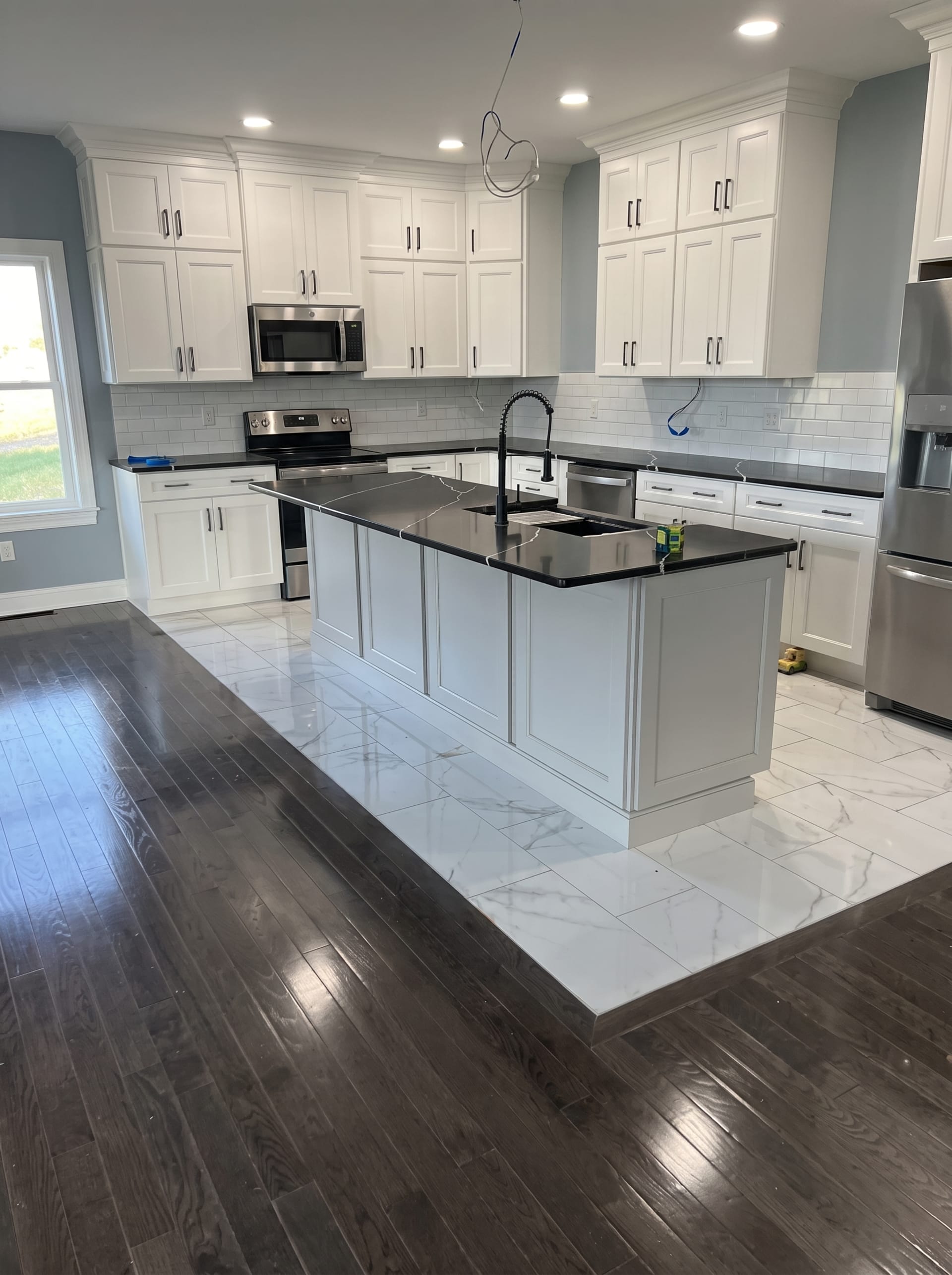 Finished kitchen remodel with a black island and waterfall quartz countertop, AZ Home Remodeling