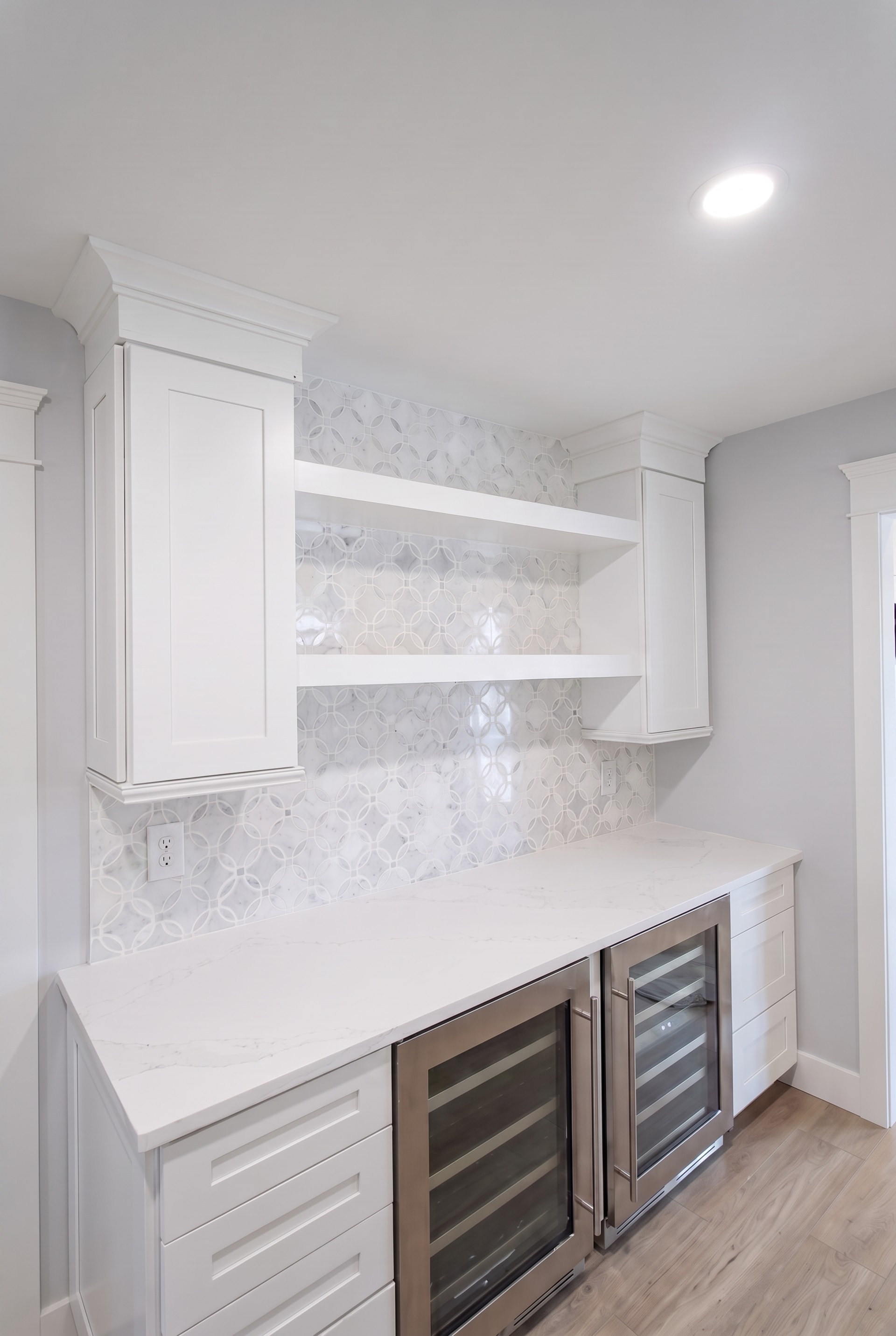 Finished wet bar with hexagon mosaic tile backsplash and open shelving