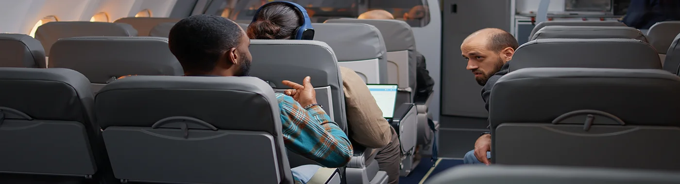 Passengers seated on an Alaska Airlines flight discussing during travel, showing comfortable cabin seats and relaxed atmosphere.