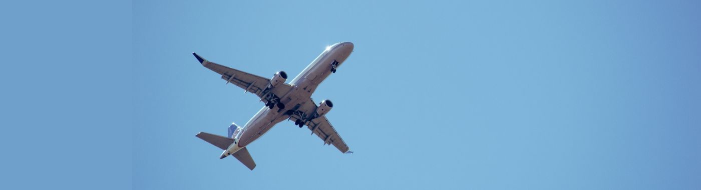 Traveler canceling a Frontier Airlines flight on laptop with Frontier plane in background