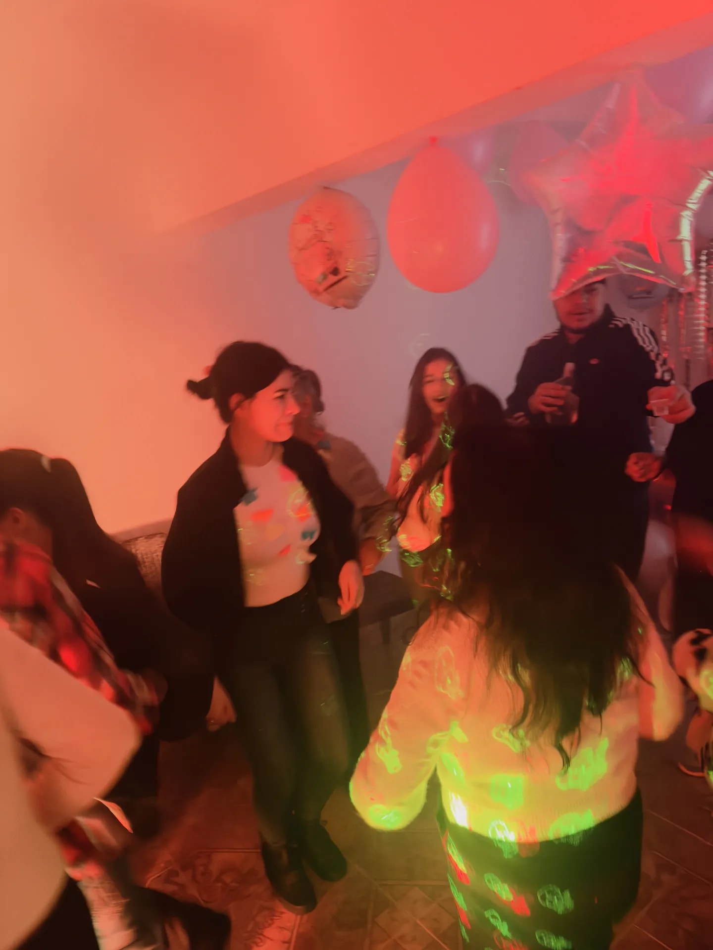 Fiesta en casa con luces neón y DJ en Bogotá: pista de baile llena — La Rumbería