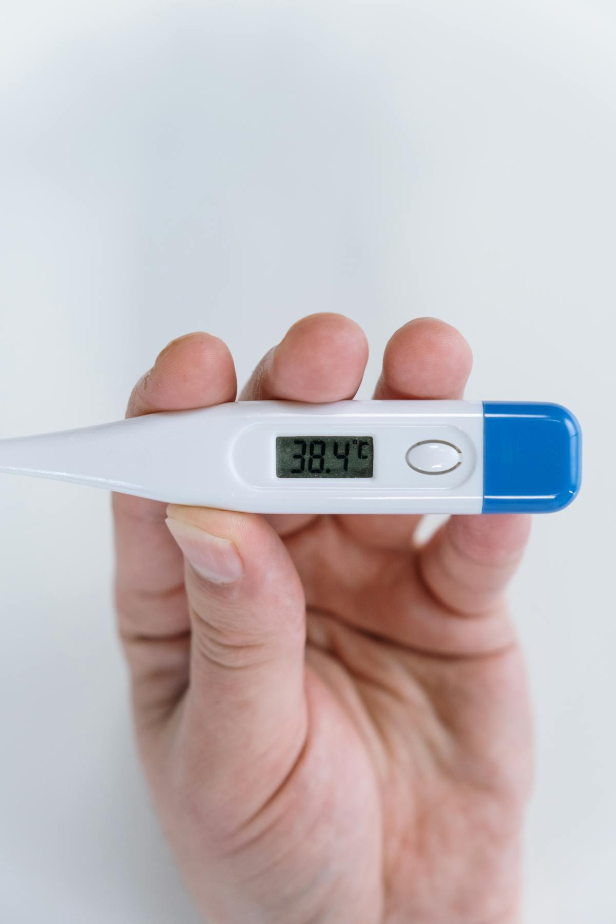 Person holding thermometer at 38.4°C — fever