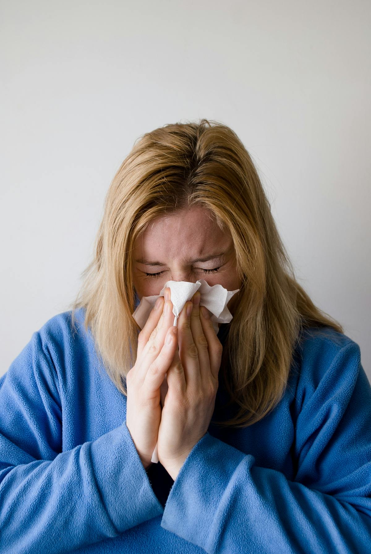 Sick woman wiping nose with tissue