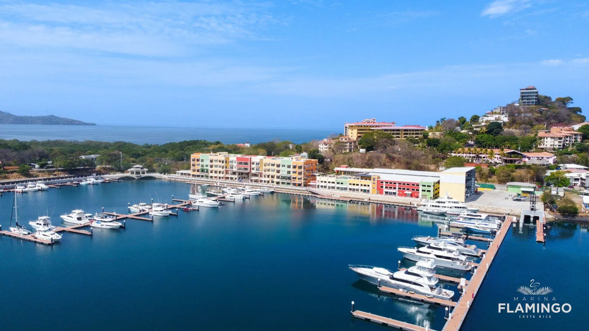 Yachts docked at Marina Flamingo beside modern waterfront buildings and tropical hills in Guanacaste, Costa Rica