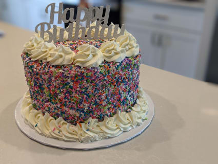 Birthday cake decorated with sprinkles and a happy birthday sign