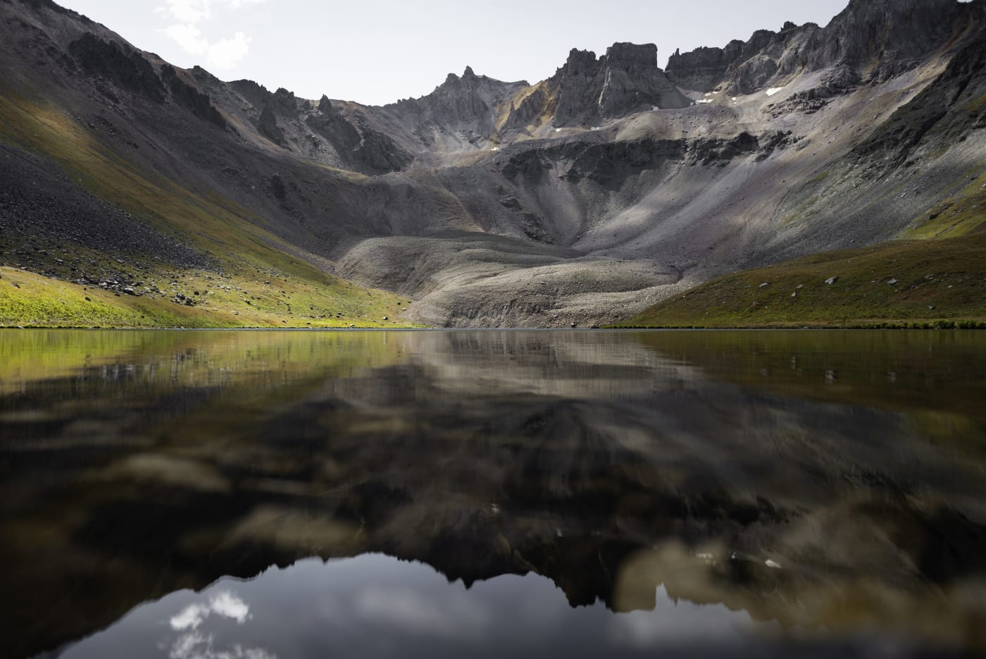A still alpine lake reflecting jagged grey peaks