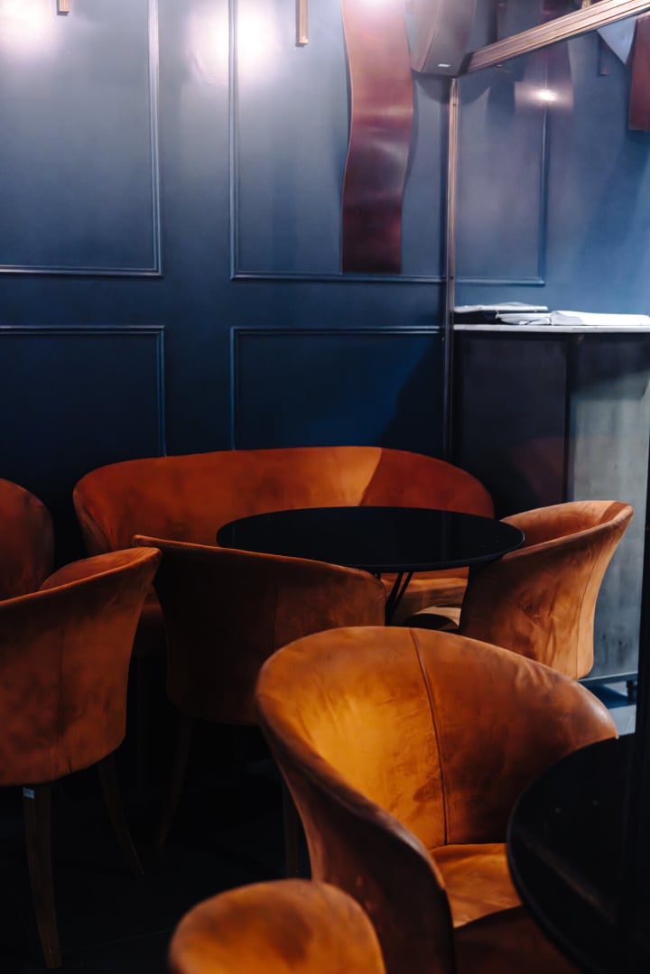 Fauteuils en velours orange contre les murs bleu nuit