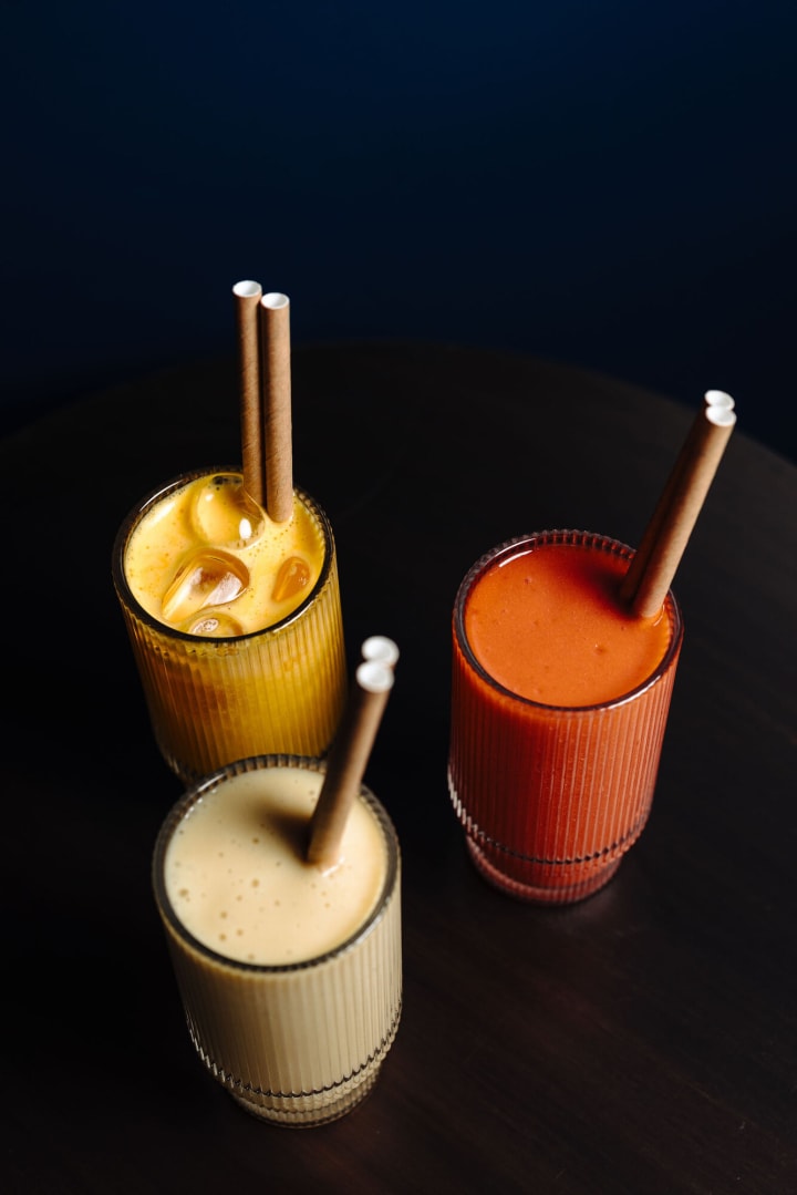 Trois jus frais pressés sur une table noire