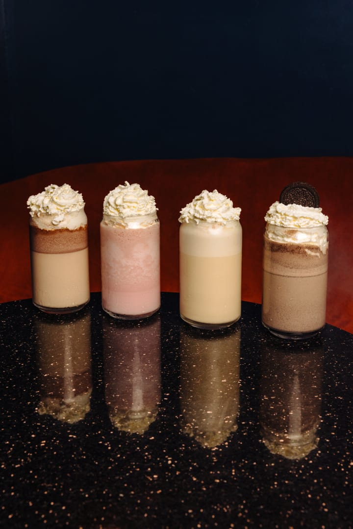 Quatre milkshakes chantilly alignés devant le velours orange