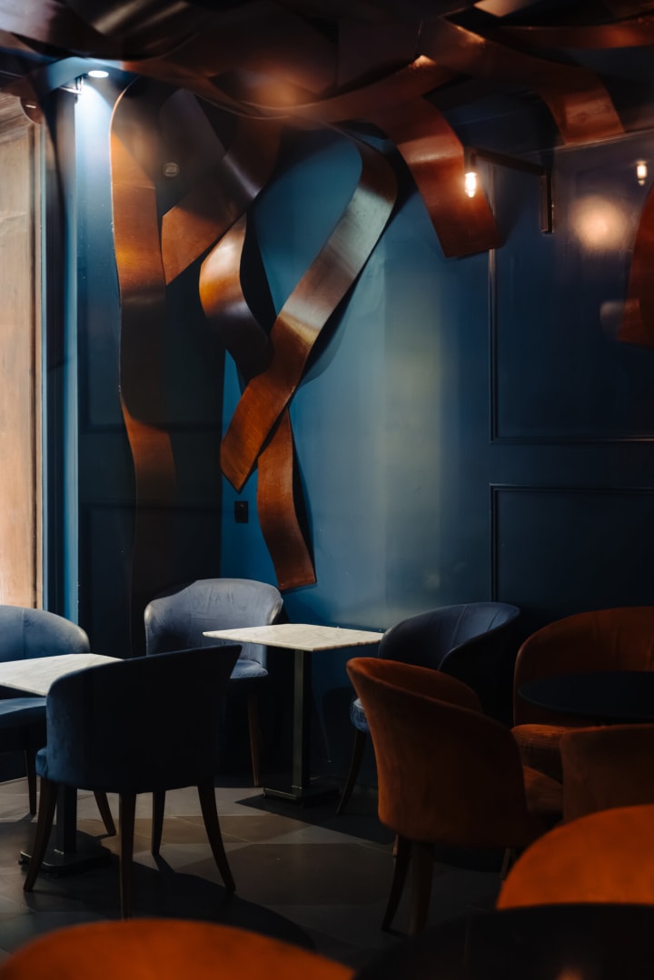 La salle du Pacific Lounge : murs bleu nuit, fauteuils en velours et rubans de cuivre au plafond
