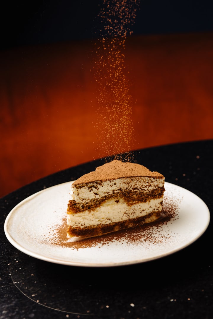 Part de tiramisu maison sous une pluie de cacao