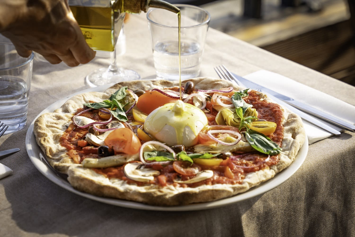 Filet d'huile d'olive versé sur une pizza burrata