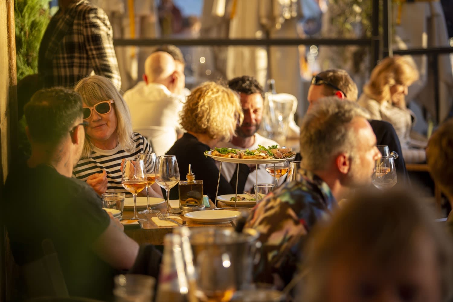 Convives à table en terrasse au coucher du soleil