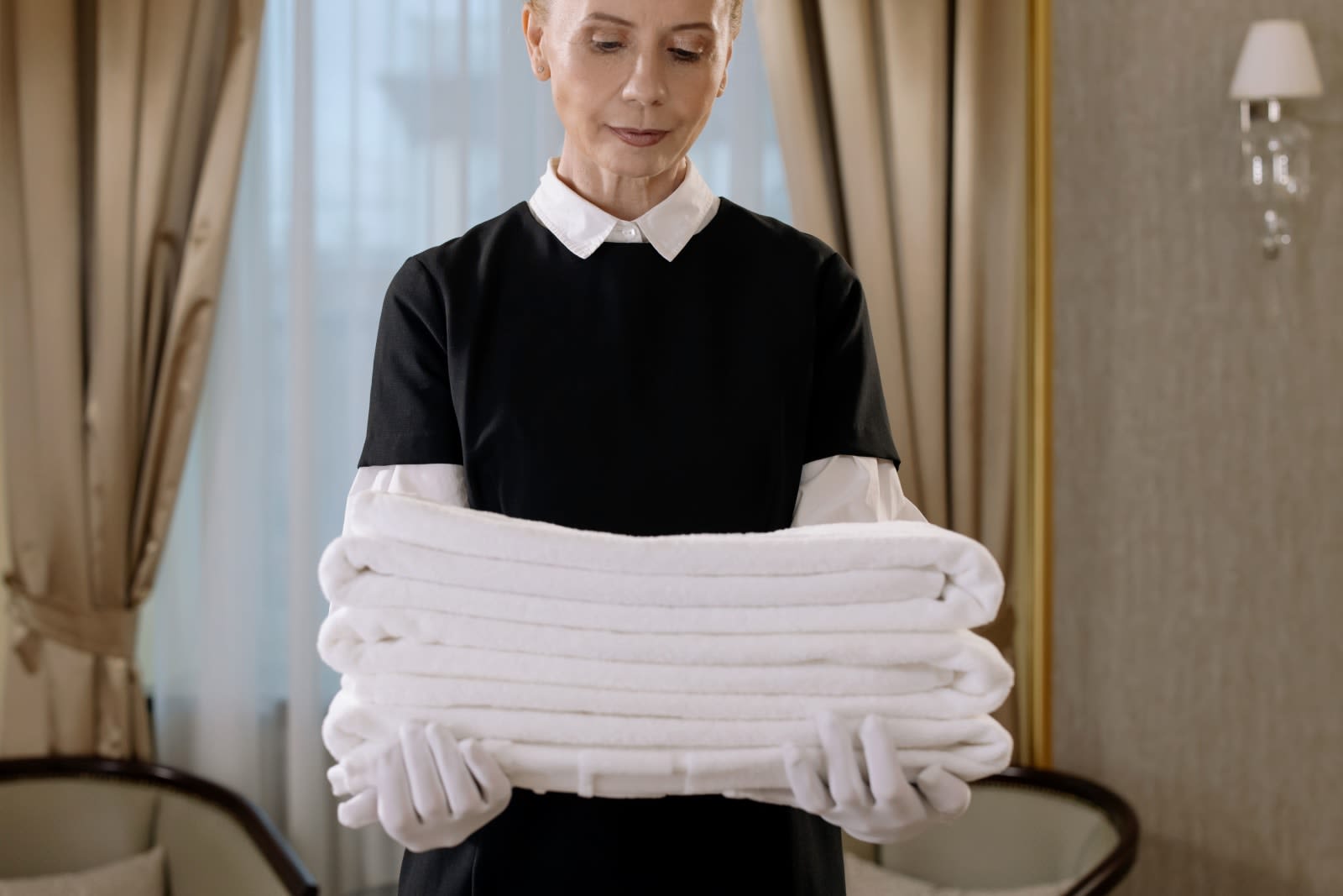 Housekeeper carrying a stack of fresh folded towels