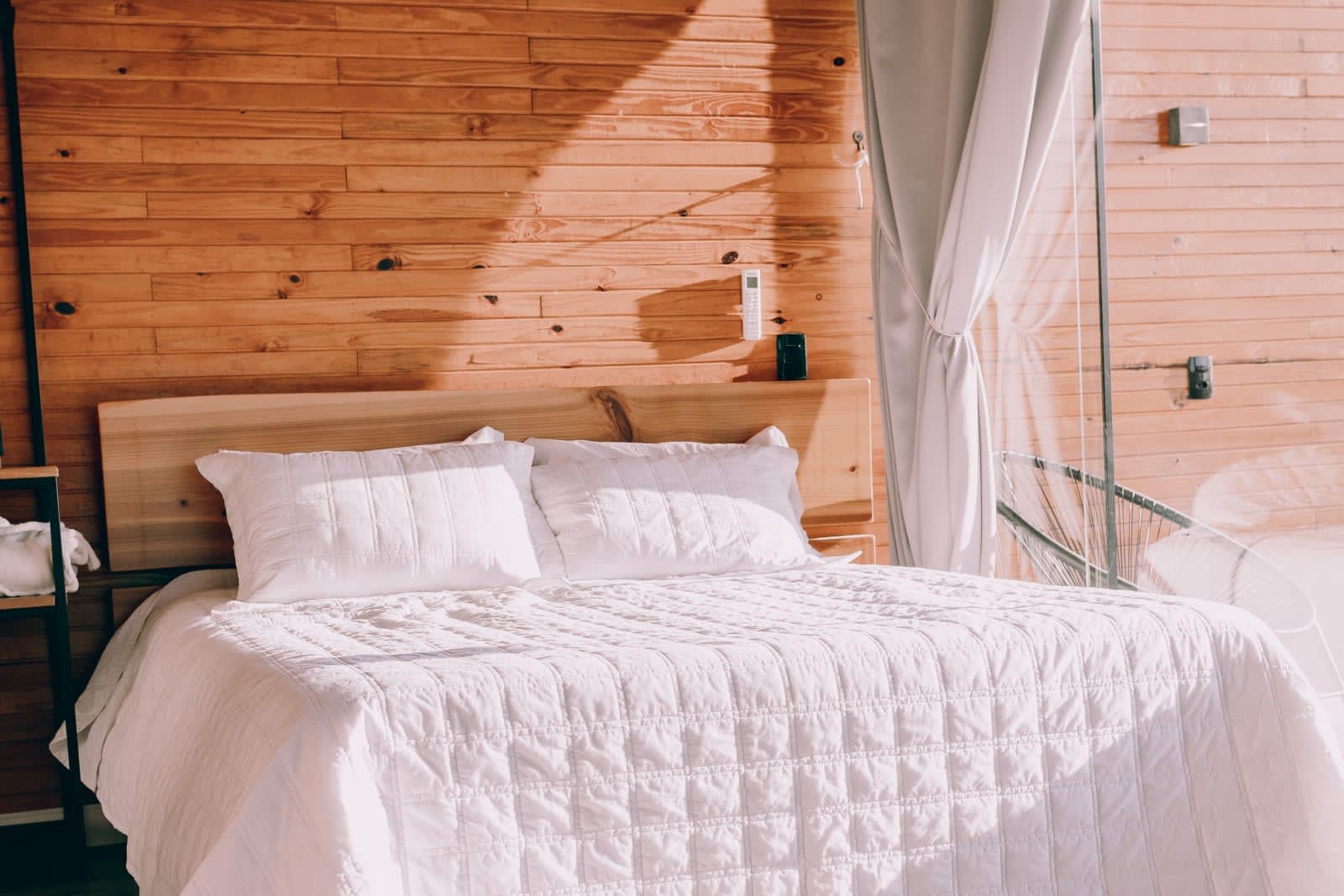 Clean, turned cabin bedroom with white bedding and wood walls