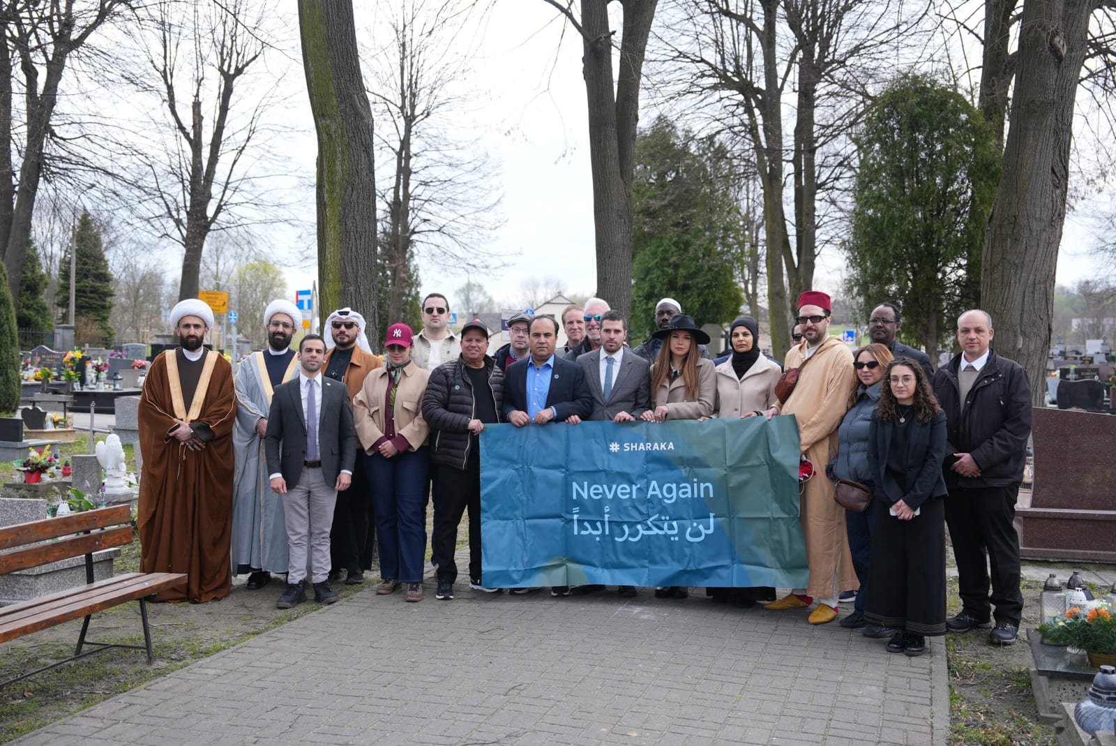 Sharaka delegation holding the Never Again banner at a cemetery