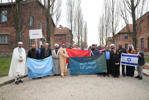 Delegation with the Never Again banner outside the Auschwitz barracks