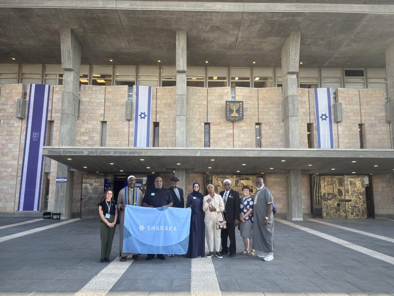 Sharaka delegation holding the Sharaka banner outside the Knesset