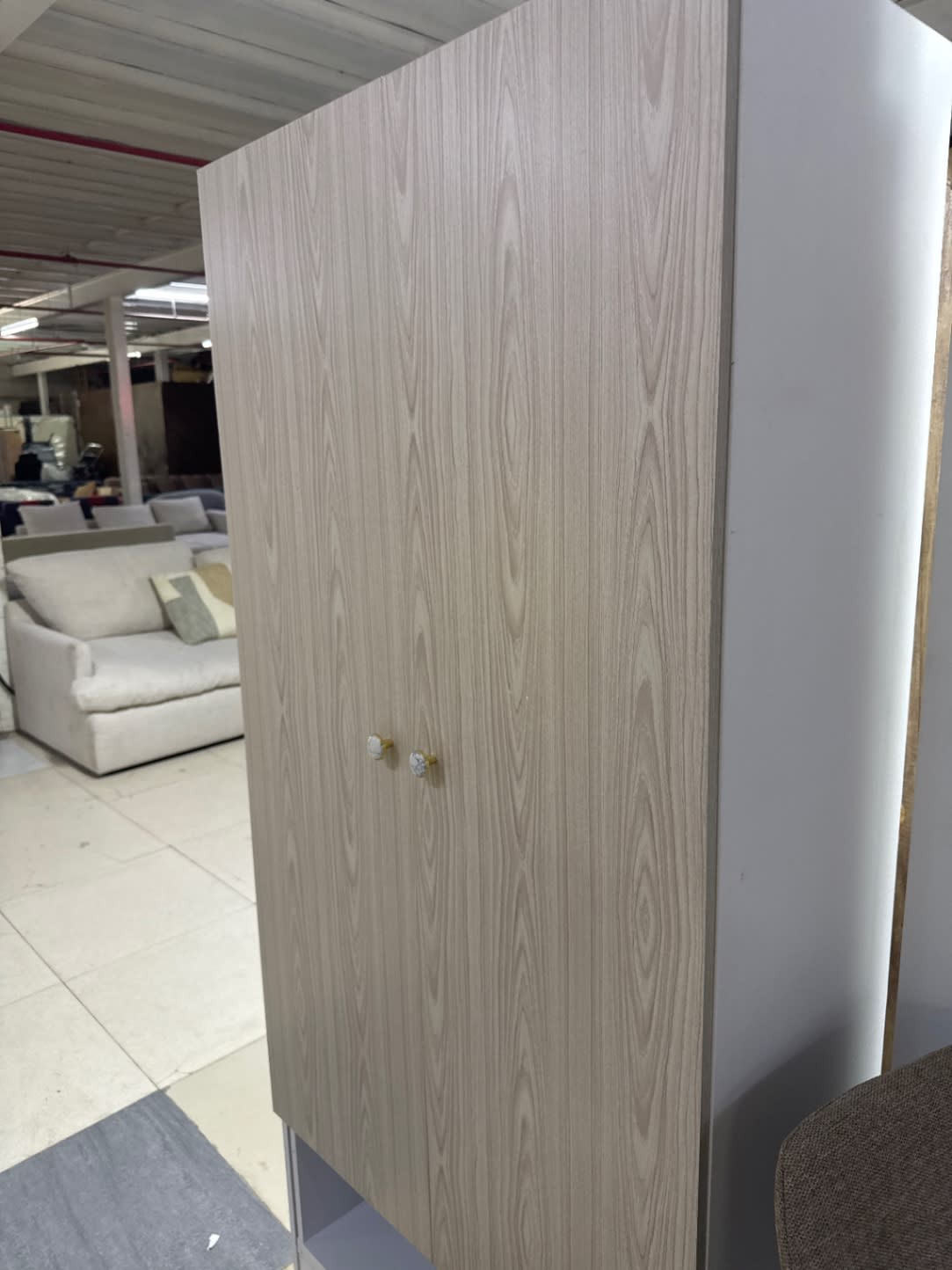 New 2-door storage cupboard angle view showing light oak doors and white side panel at Bufaisal Shop B Ajman