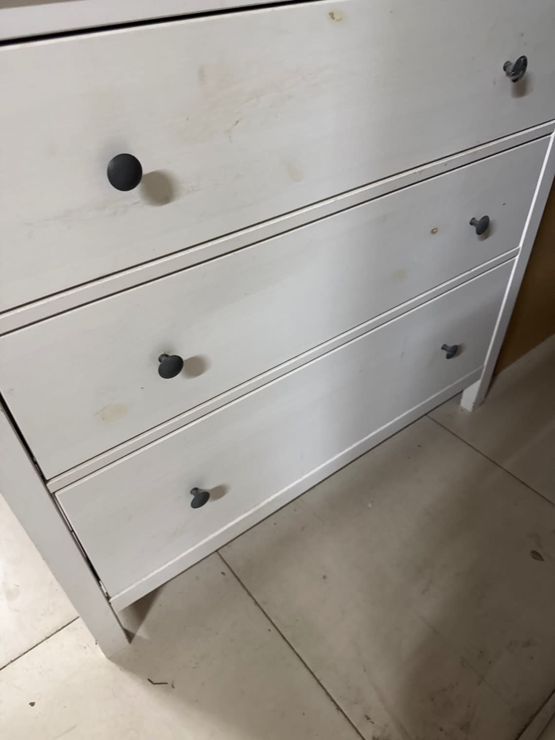 Close-up front angle of used white 3-drawer dresser showing surface condition